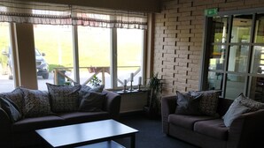 A room with two sofas, a coffee table, and large windows with a view of the outside. - Highway (Harnosand)