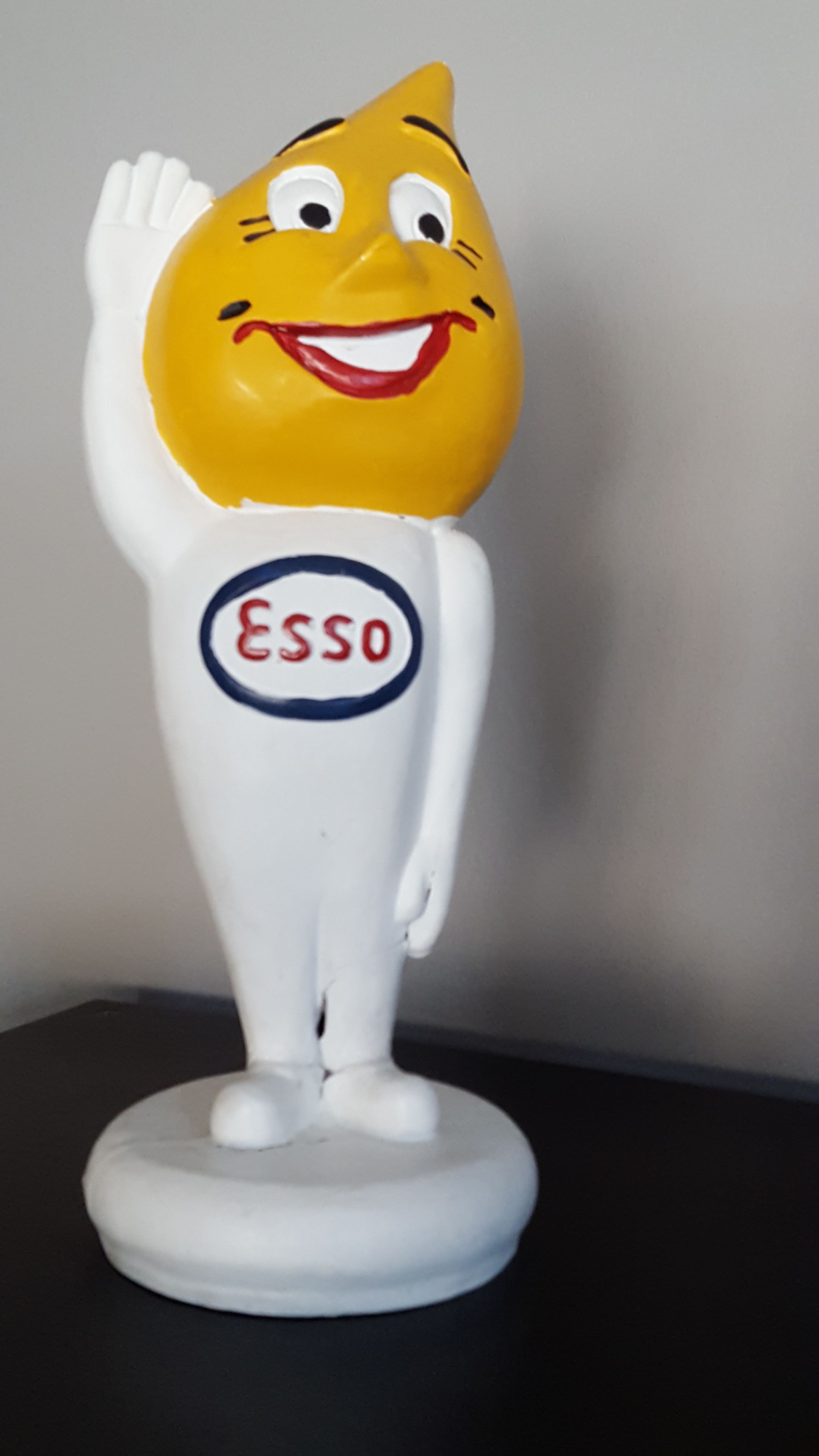 A figurine with a yellow head, a white body, and a red and blue logo that reads "Esso."