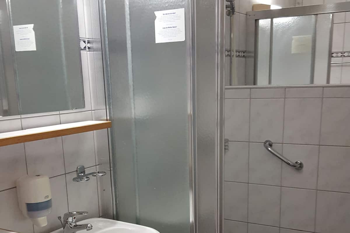 Eenvoudige eenpersoonskamer | Badkamer | Een douche, een haardroger, handdoeken