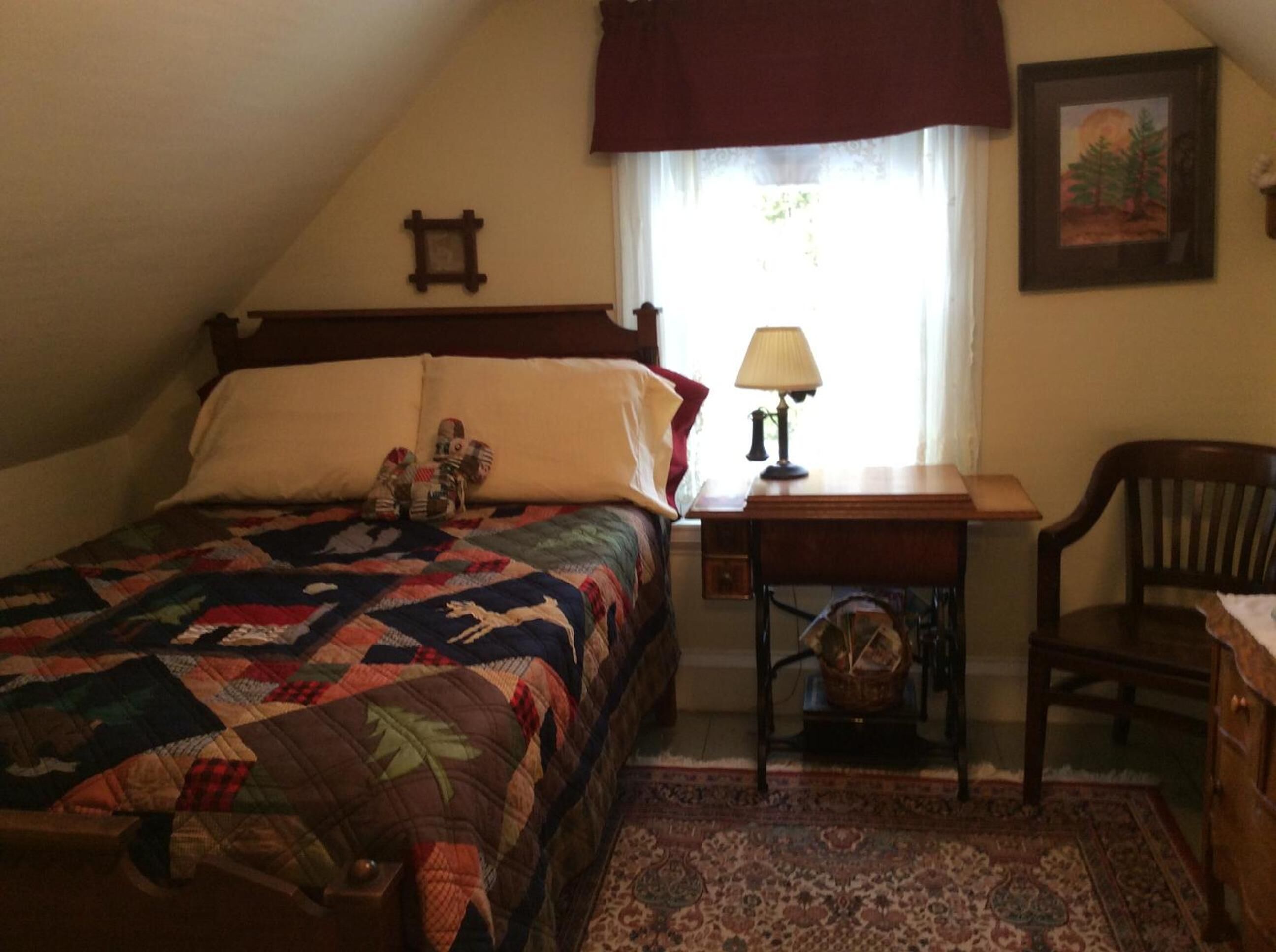 A bedroom with a bed, a desk, a chair, a lamp, and a window with curtains.