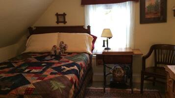 A bedroom with a bed, a desk, a chair, a lamp, and a window with curtains.