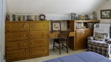 Une chambre à coucher avec une commode en bois, un bureau avec des livres, une chaise et un lit.