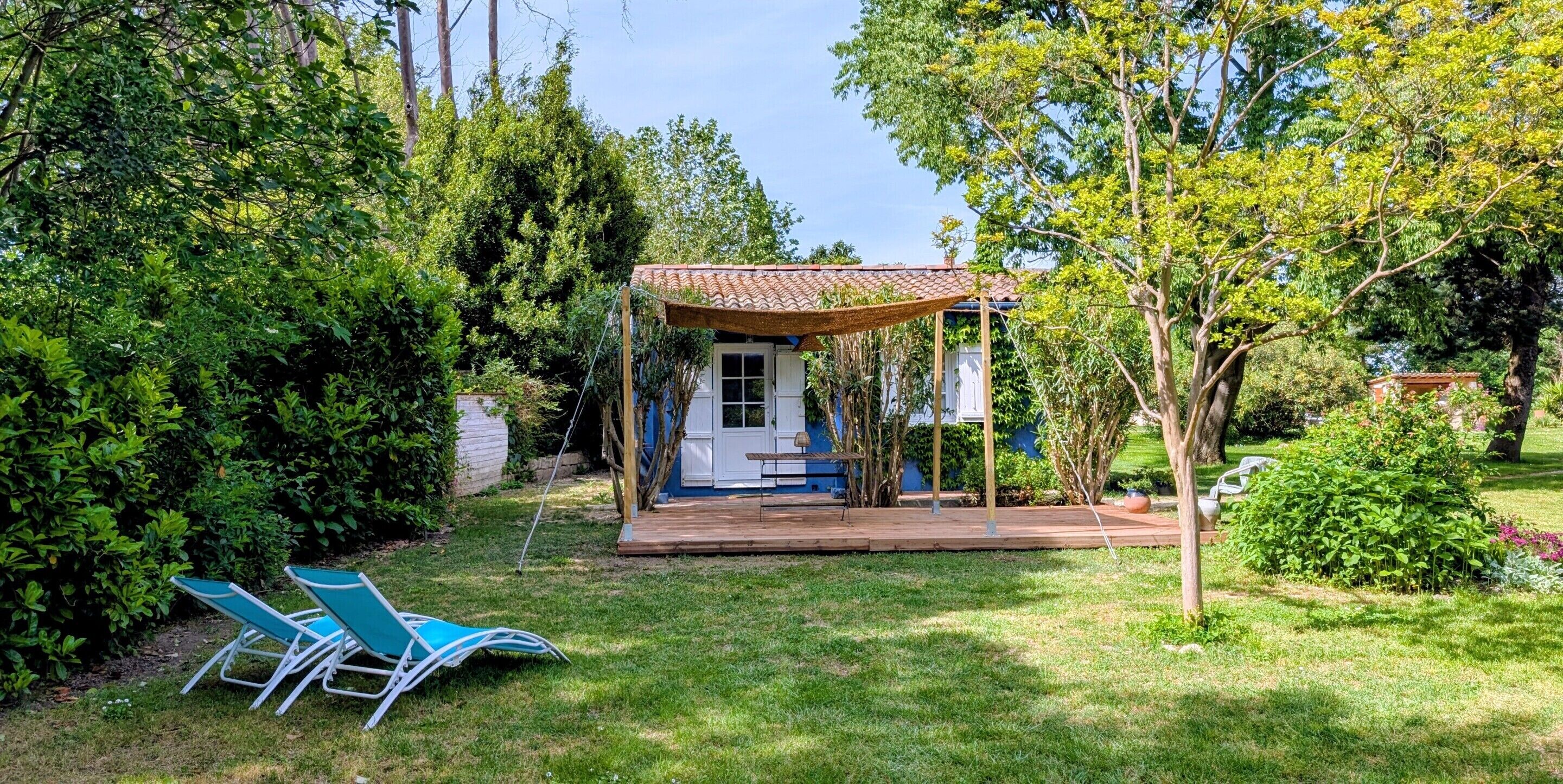 A small house with a porch, surrounded by lush greenery and trees.