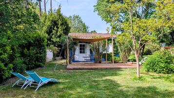 A small house with a porch, surrounded by lush greenery and trees.