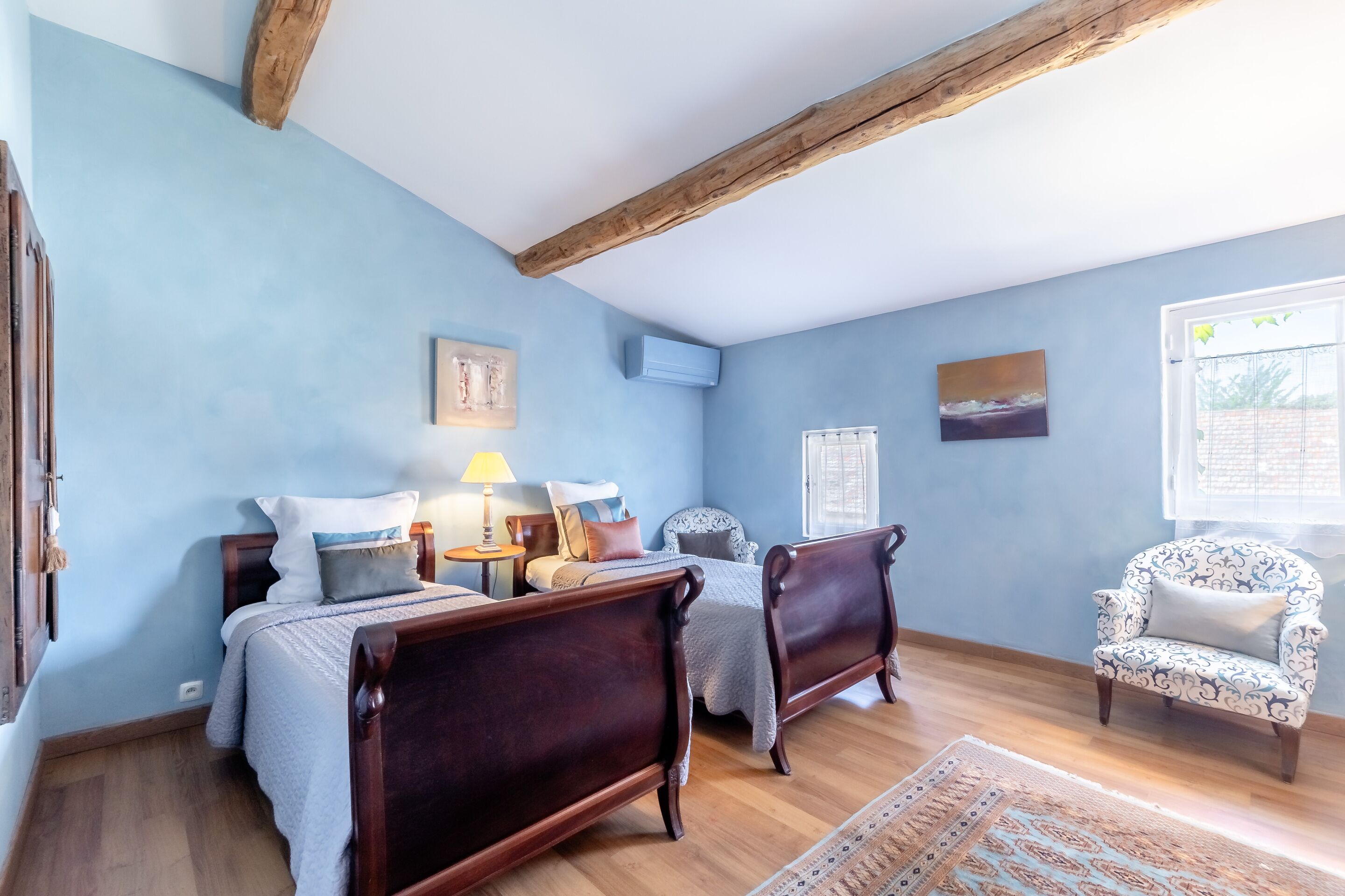 Une chambre à coucher avec un lit en bois, une chaise et une fenêtre.