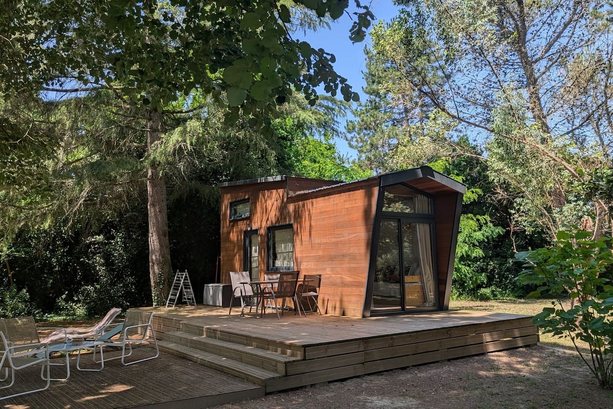 Uma cabana de madeira com varanda, área de estar e grandes janelas.