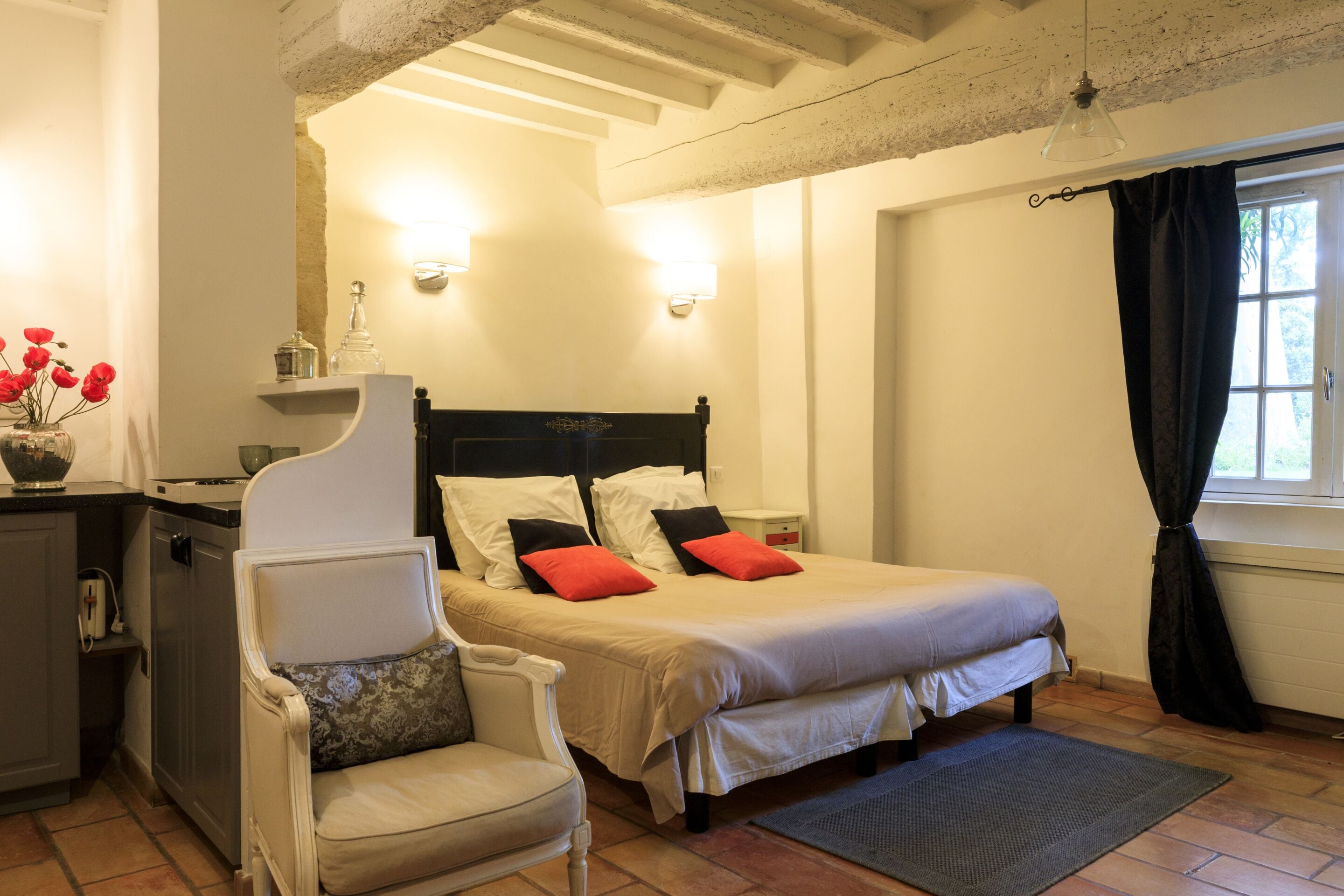 A bedroom with a bed, a chair, a desk, and a window with curtains.