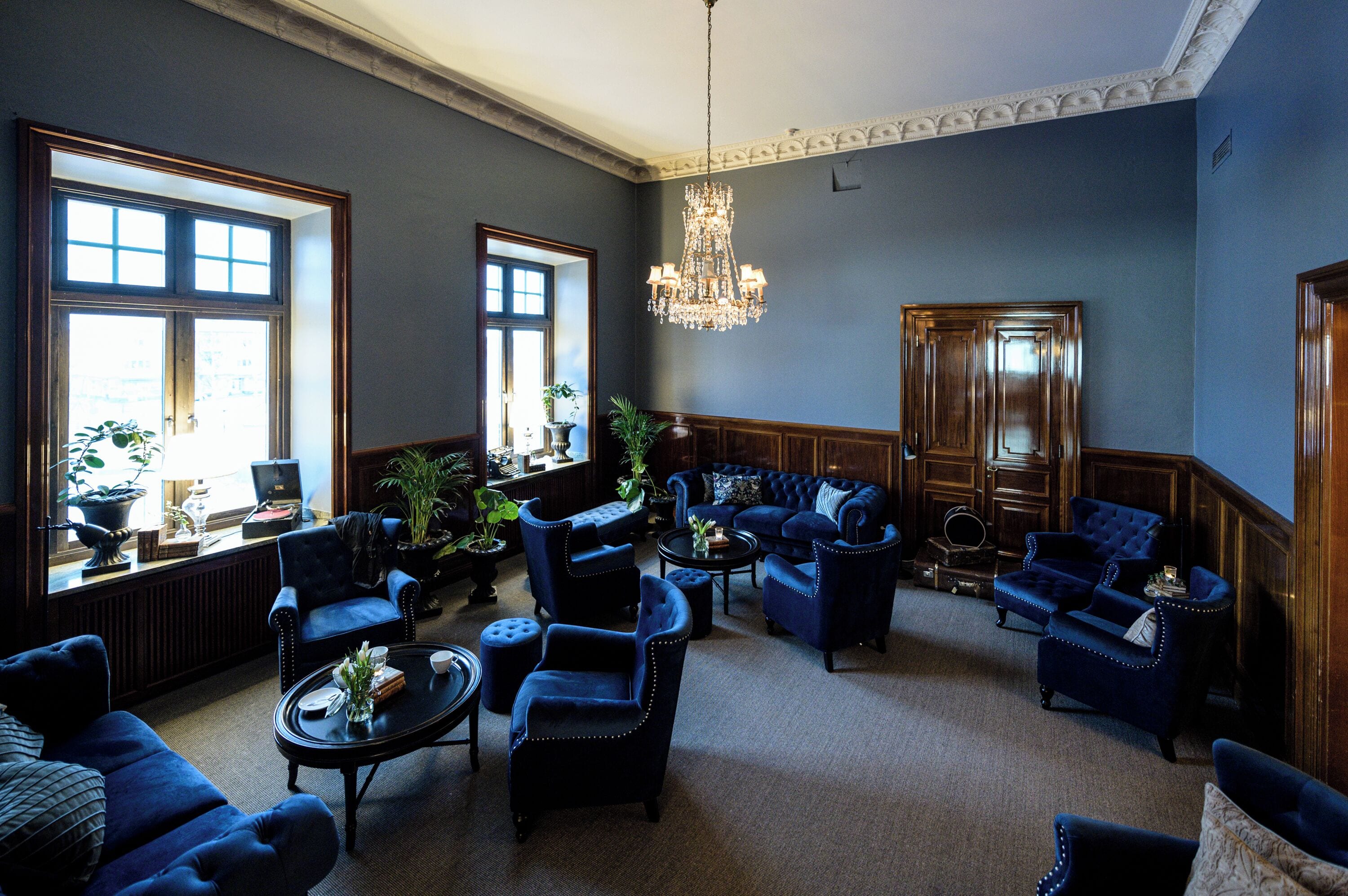 Uma sala de estar ampla com vários espaços de estar, janelas grandes e um candelabro.