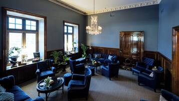 Uma sala de estar ampla com vários espaços de estar, janelas grandes e um candelabro.
