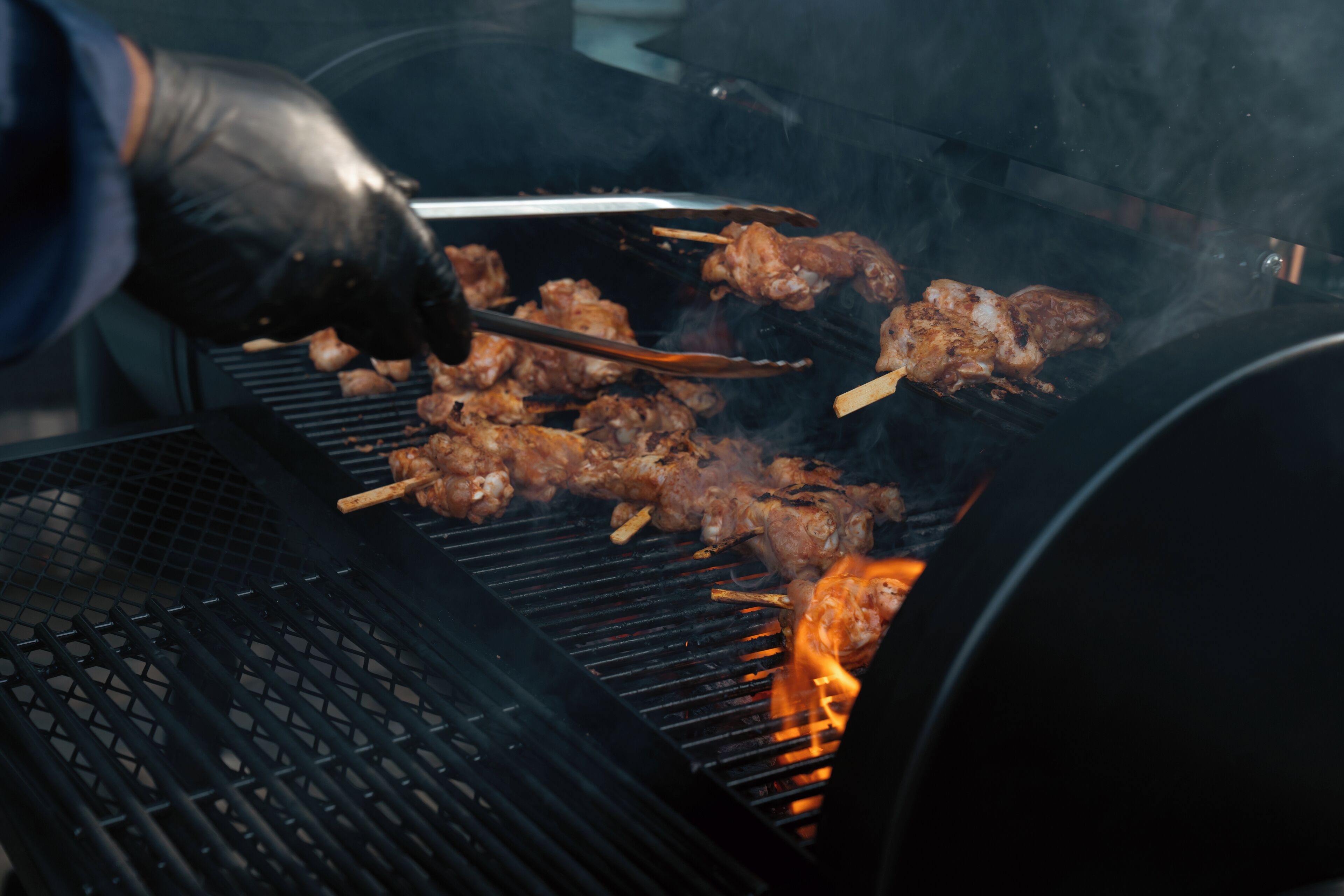 Una parrilla con brochetas de carne asándose.