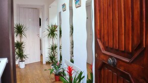 A hallway with wooden flooring, potted plants, and a wooden door with a brass handle. - Villa Achibea (Agrigento)