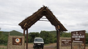A vehicle entering a wildlife camp with a stone archway and a welcome sign.