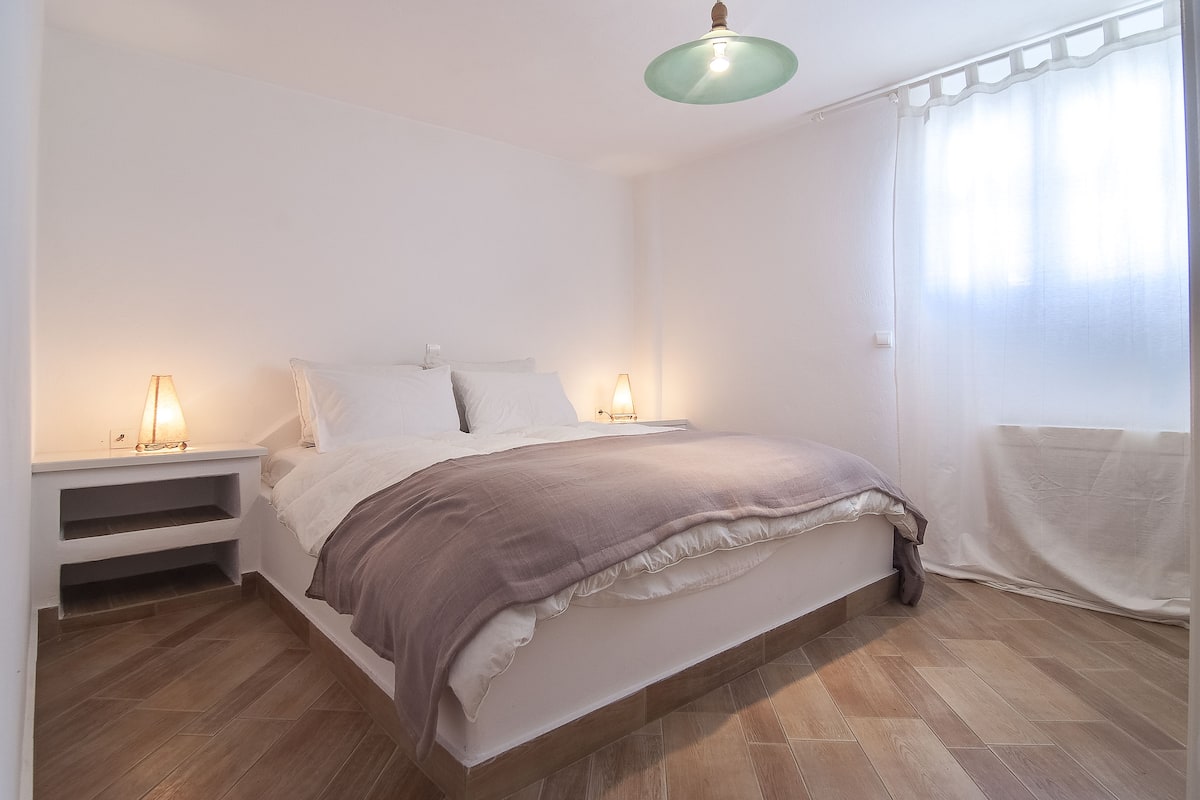 Une chambre à coucher avec un lit, des tables de chevet et un luminaire suspendu.