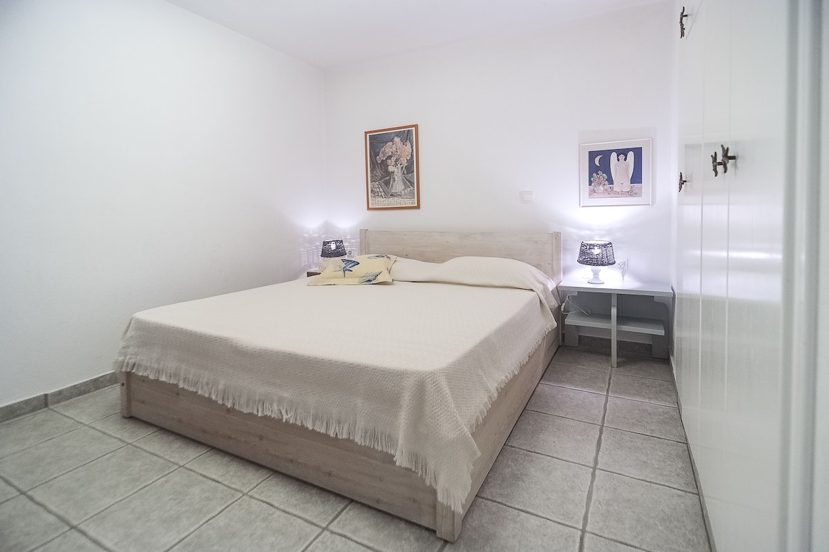 Une chambre à coucher avec un lit, des tables de chevet et des œuvres d’art murales.