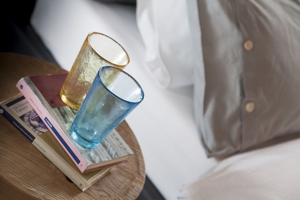 A wooden side table with two glasses, a book, and some papers.