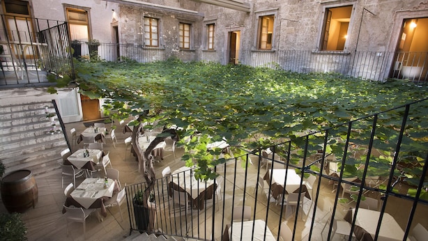 Un patio con mesas y sillas, una escalera y un edificio con ventanas.