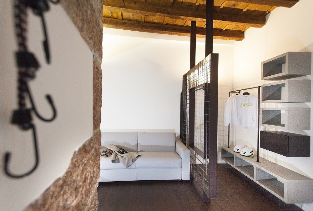 Ein modernes Badezimmer mit Waschbecken, Spiegel und Handtuchhalter. Im Hintergrund steht ein weißes Sofa und ein Regal mit Schuhen und einem Helm.