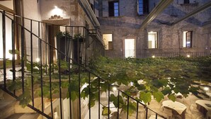 Un patio con mesas al aire libre, una escalera y la fachada de un edificio de piedra.