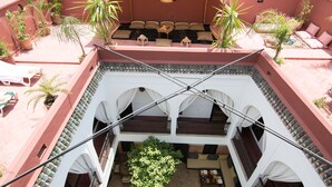 A rooftop terrace with a seating area, potted plants, and a view of the interior courtyard. - Riad El Gnaouia (Marrakech)