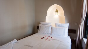 A neatly made bed with white linens and a decorative pillow arrangement. - Riad El Gnaouia (Marrakech)