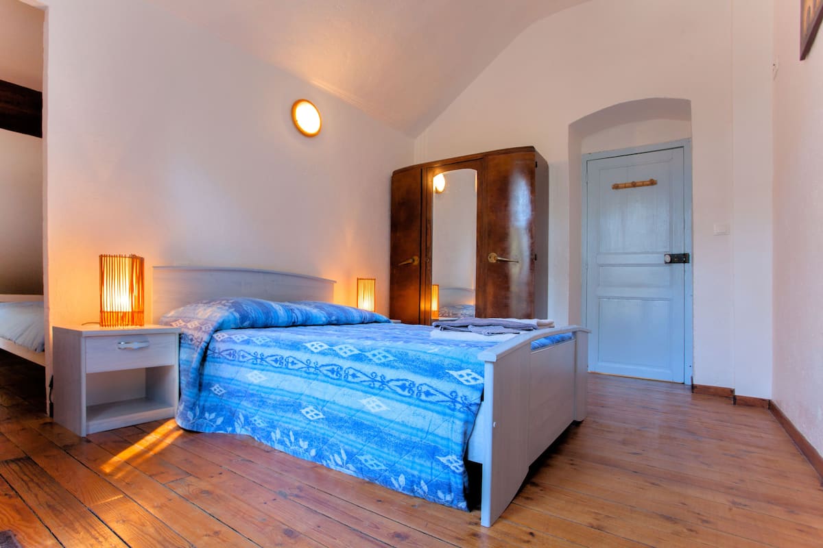 Une chambre à coucher avec un lit, des tables de chevet, un miroir et une porte.