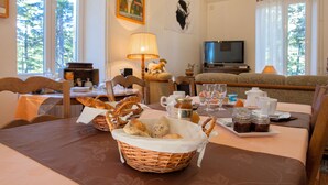 Un coin repas avec une table mise pour le petit-déjeuner, comprenant du pain, des viennoiseries et des condiments.