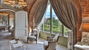 Una habitación con paredes de ladrillo abovedadas, un ventanal con cortinas y muebles elegantes.