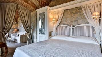 A bedroom with a large bed, stone walls, and a rustic ceiling.