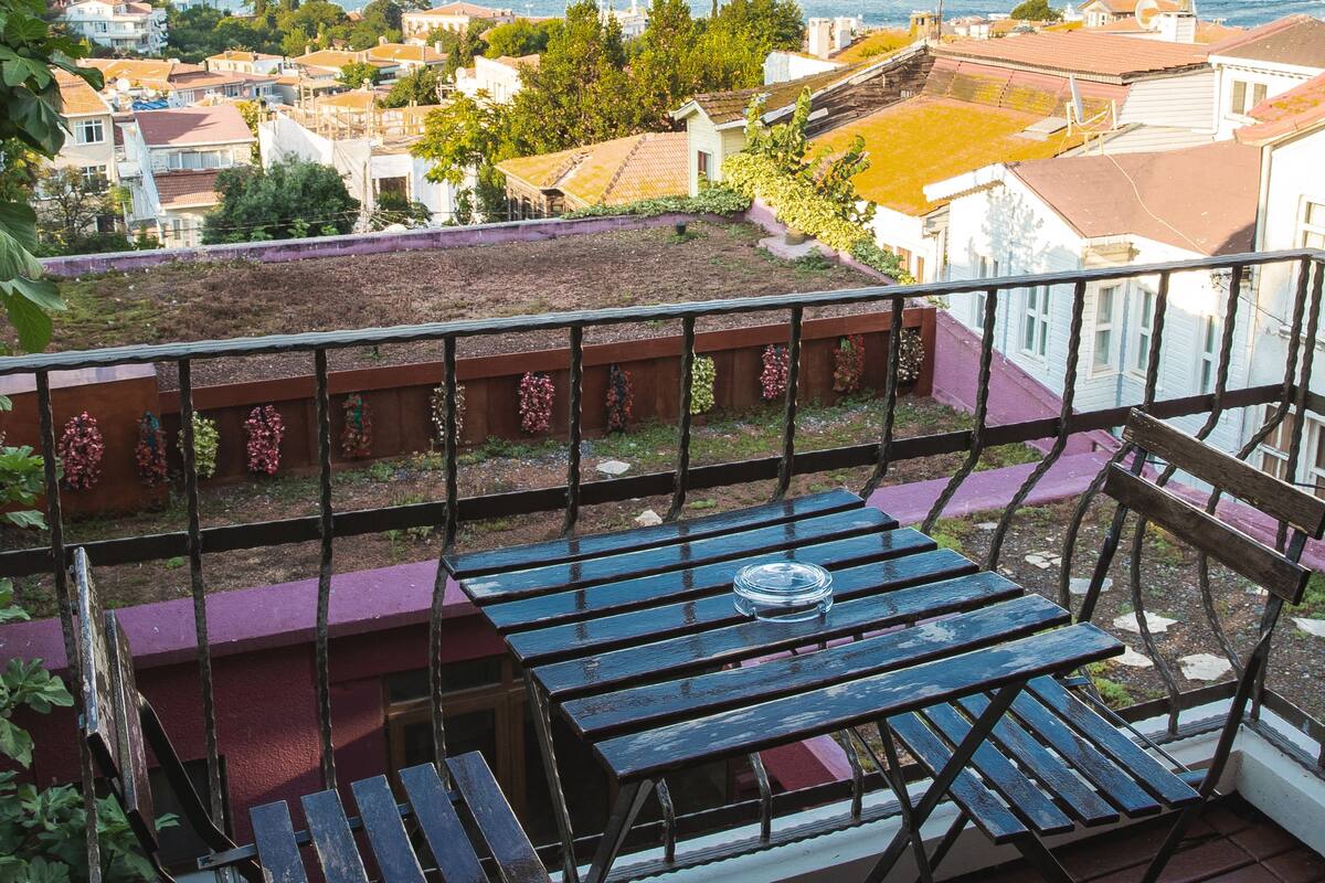 Un balcón con vistas a un paisaje urbano costero, que incluye edificios y una masa de agua.
