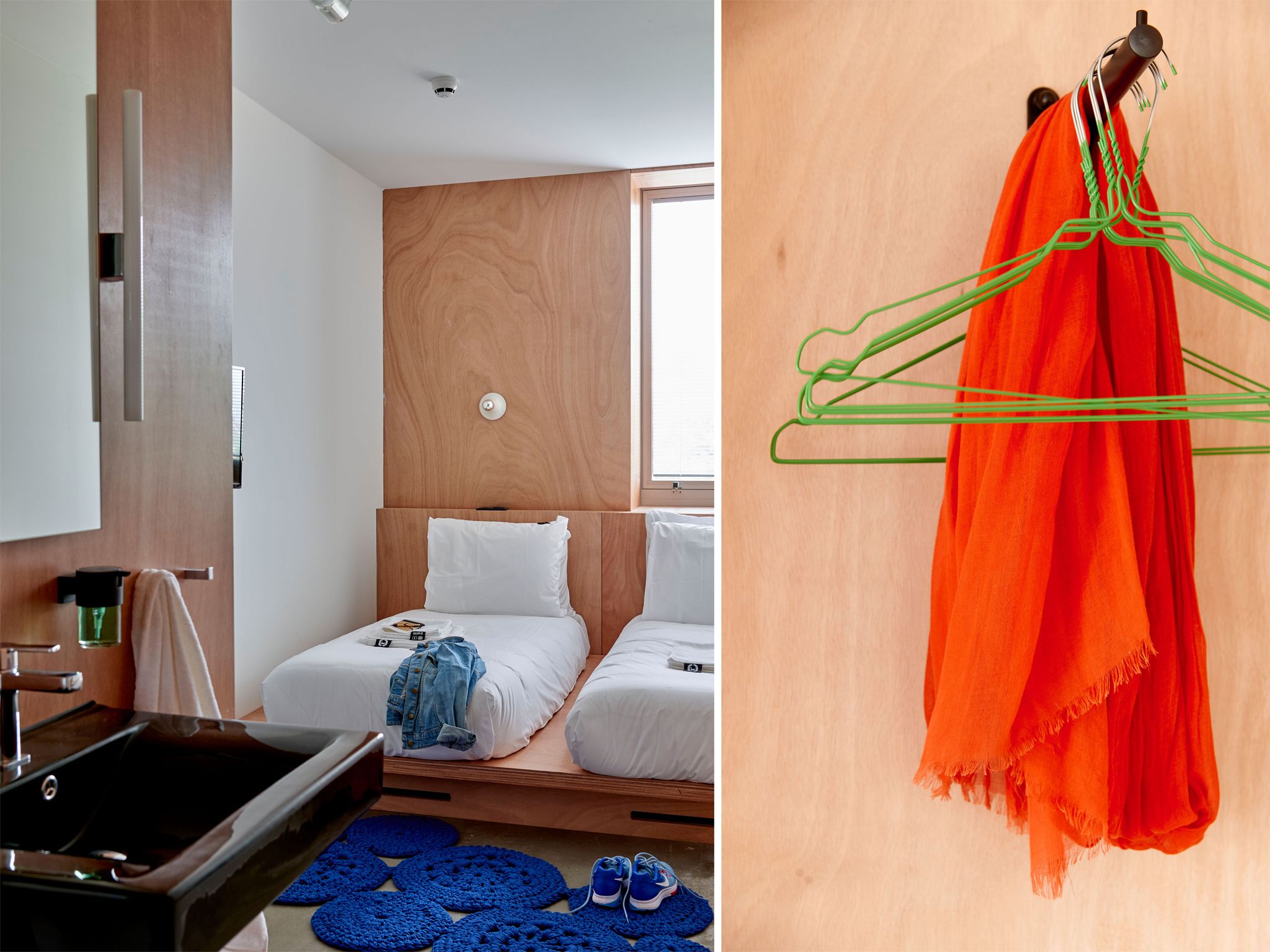 A modern hotel room with a wooden headboard, a bed with white linens, a built-in sink, and a blue circular rug.