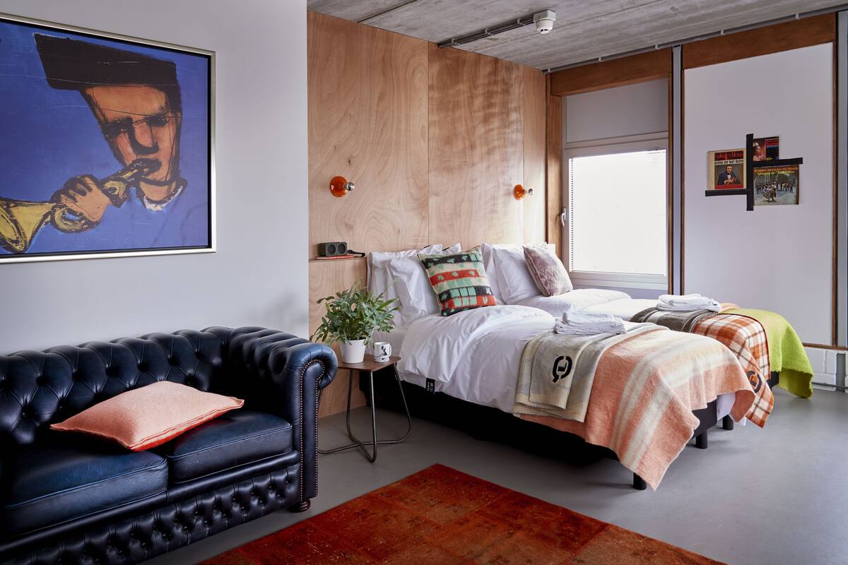 A modern bedroom with a bed, a sofa, and a painting.