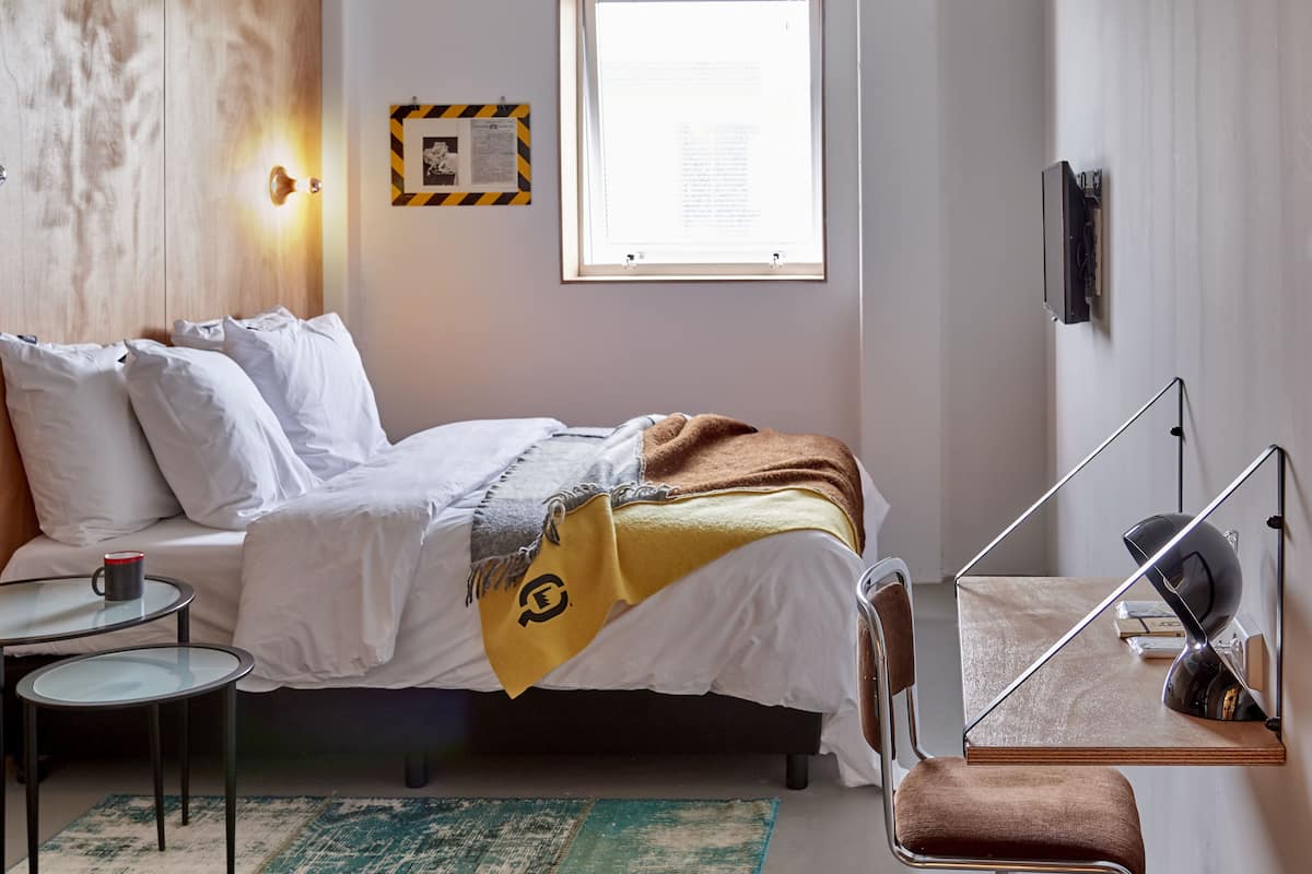 A modern bedroom with a bed, bedside tables, a desk, and a chair.
