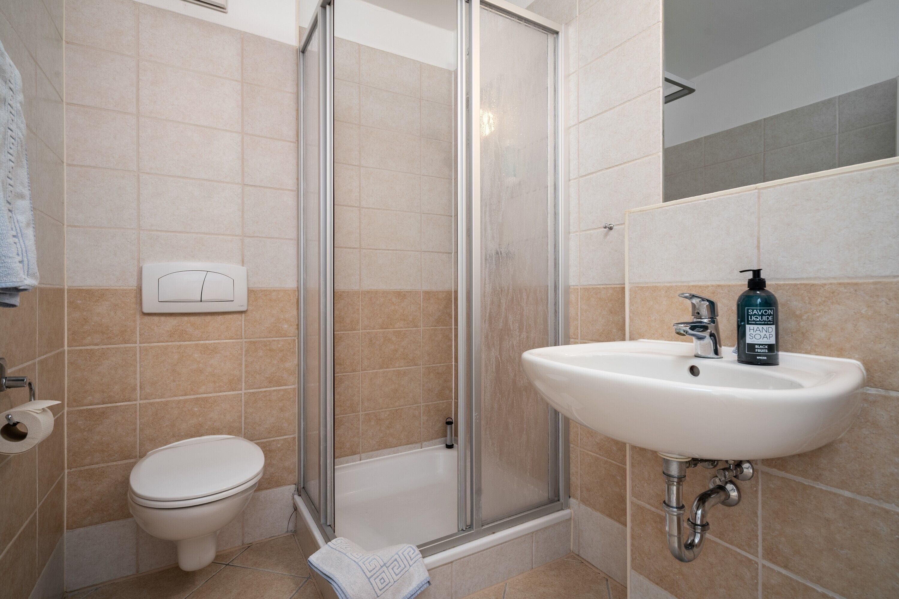 A bathroom with a toilet, shower, and sink.