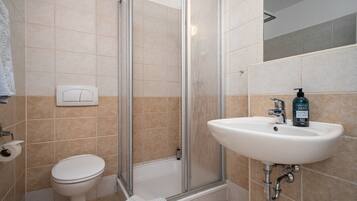 A bathroom with a toilet, shower, and sink.