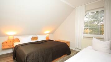 A bedroom with a bed, two bedside tables, a window with curtains, and a lamp on each table.