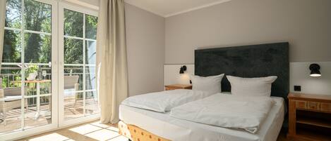 A bedroom with a large bed, a nightstand, a lamp, and a view through a sliding glass door to an outdoor area with furniture.