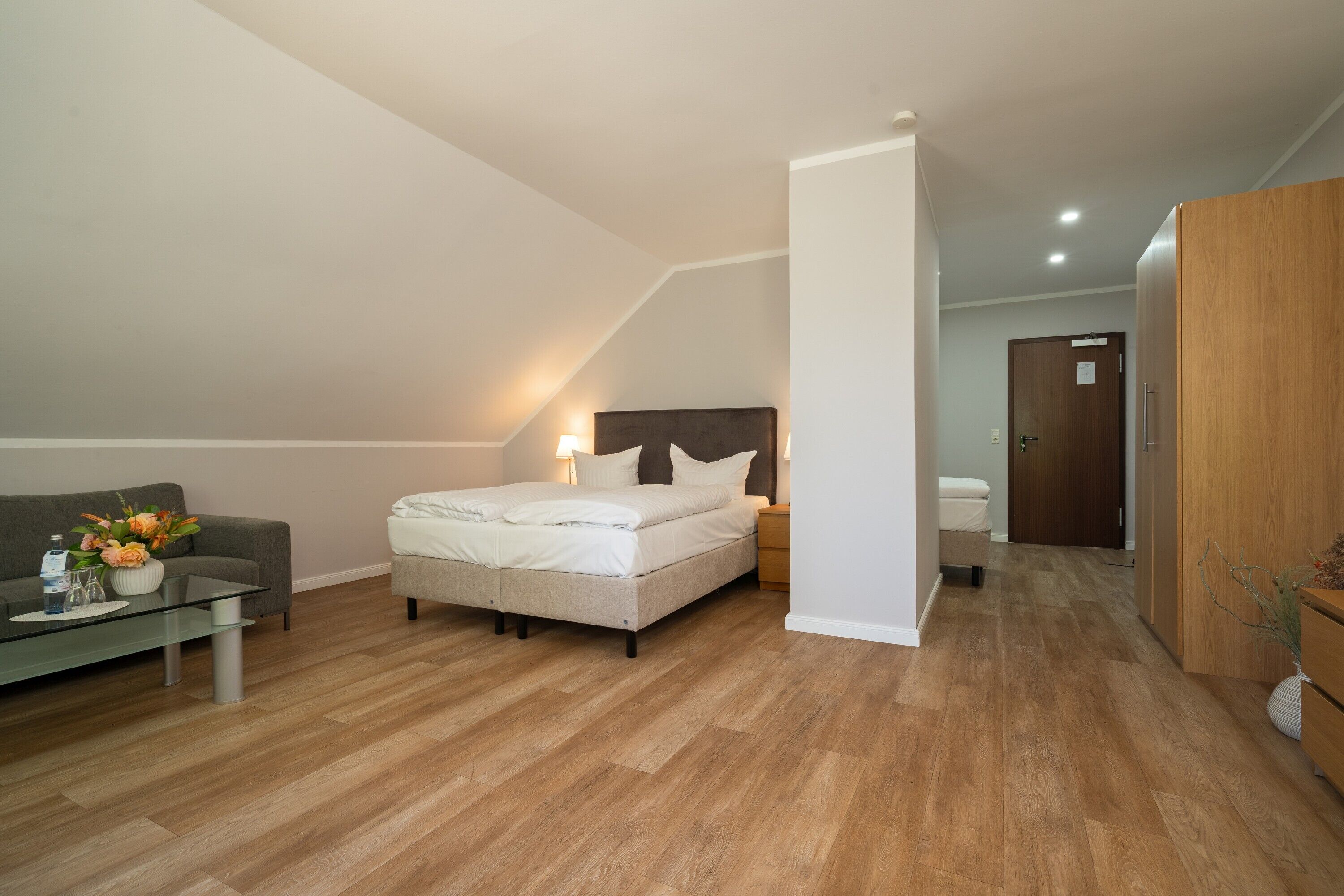 A modern bedroom with a bed, bedside table, and a sofa.