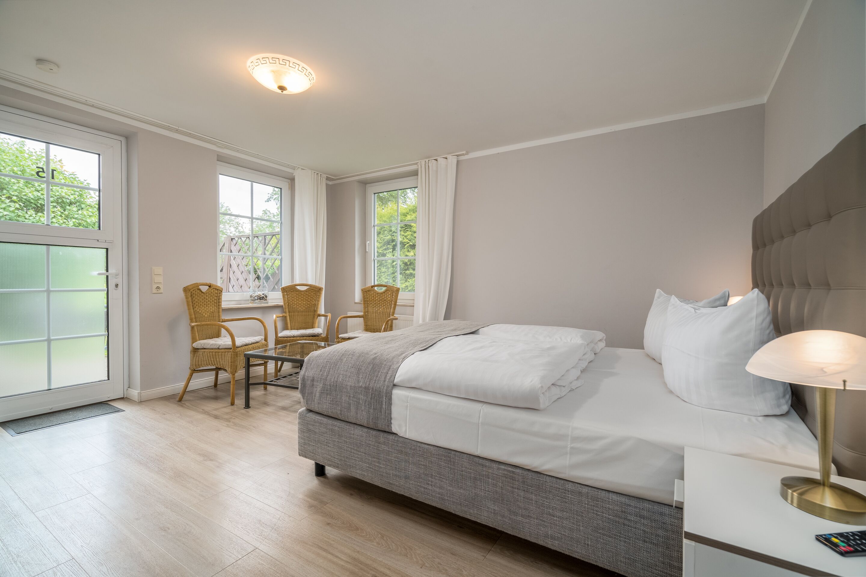 A bedroom with a bed, bedside table, lamp, and two chairs.