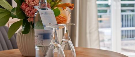 Eine Wasserflasche mit Etikett und zwei leere Weingläser auf einem runden Tisch mit Unterlage.