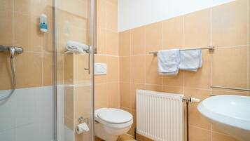 Une salle de bain avec une douche à parois de verre, des toilettes, un radiateur et un lavabo.