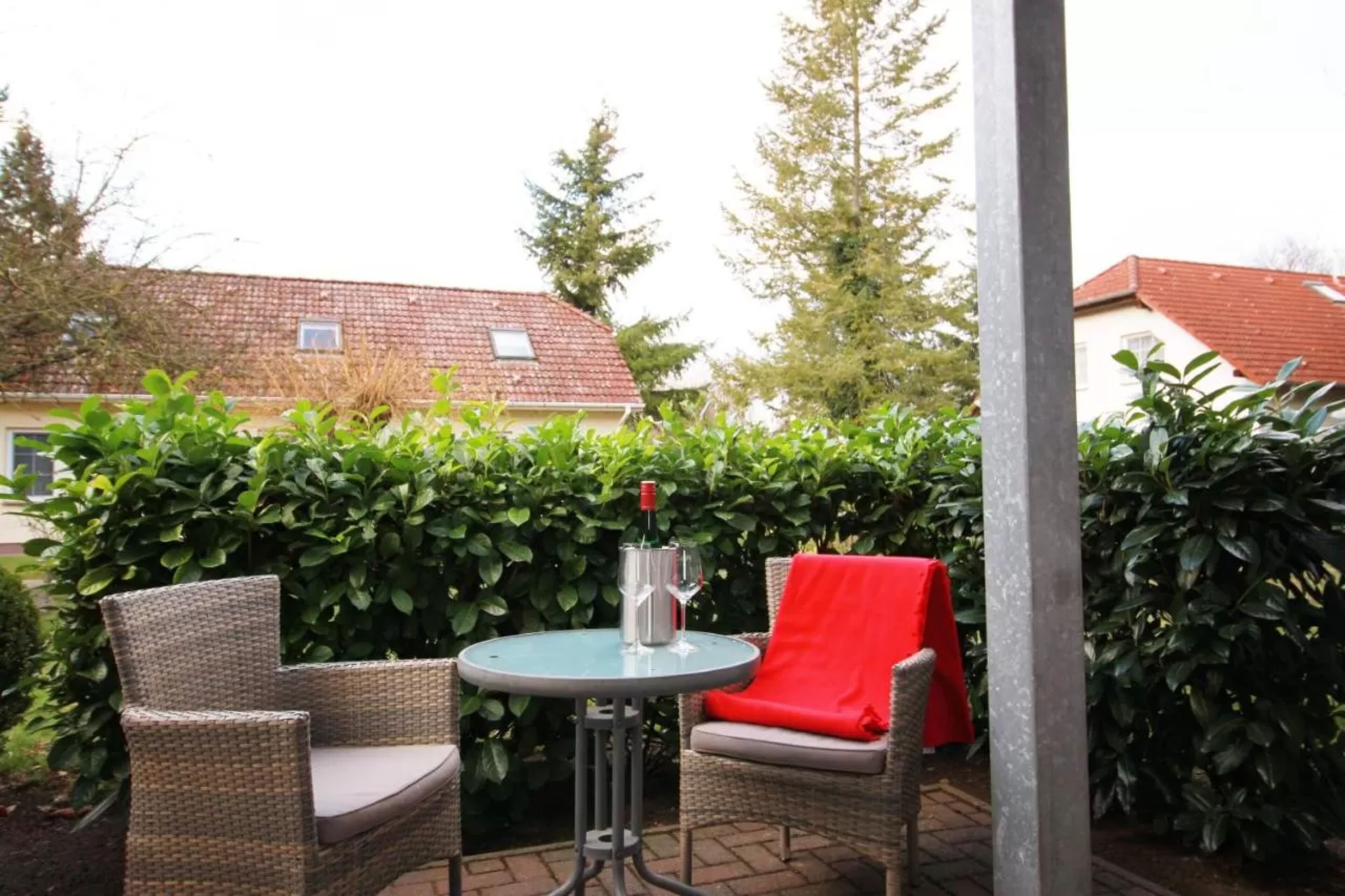 Une terrasse extérieure avec des meubles en osier, une table et une bouteille de vin.
