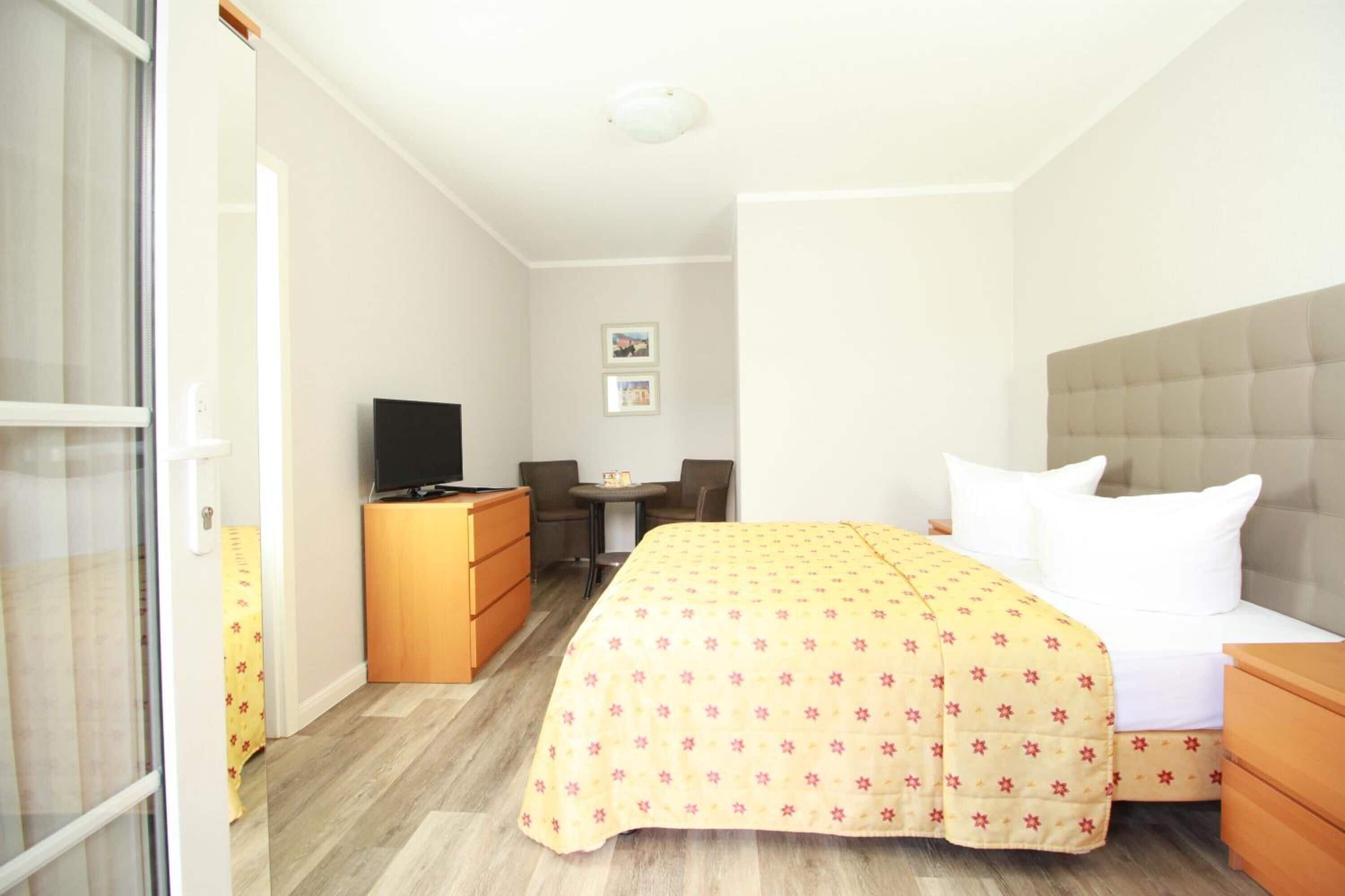 A hotel room with a bed, a TV, a desk, and a chair.