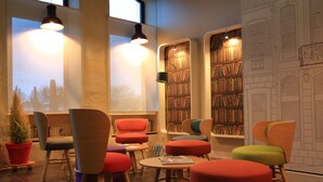 Eine Bibliothek mit mehreren Sitzbereichen, Bücherregalen und einem großen Fenster mit Blick.