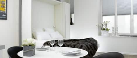 Une chambre à coucher moderne avec un lit, une table de chevet et une fenêtre avec des stores.