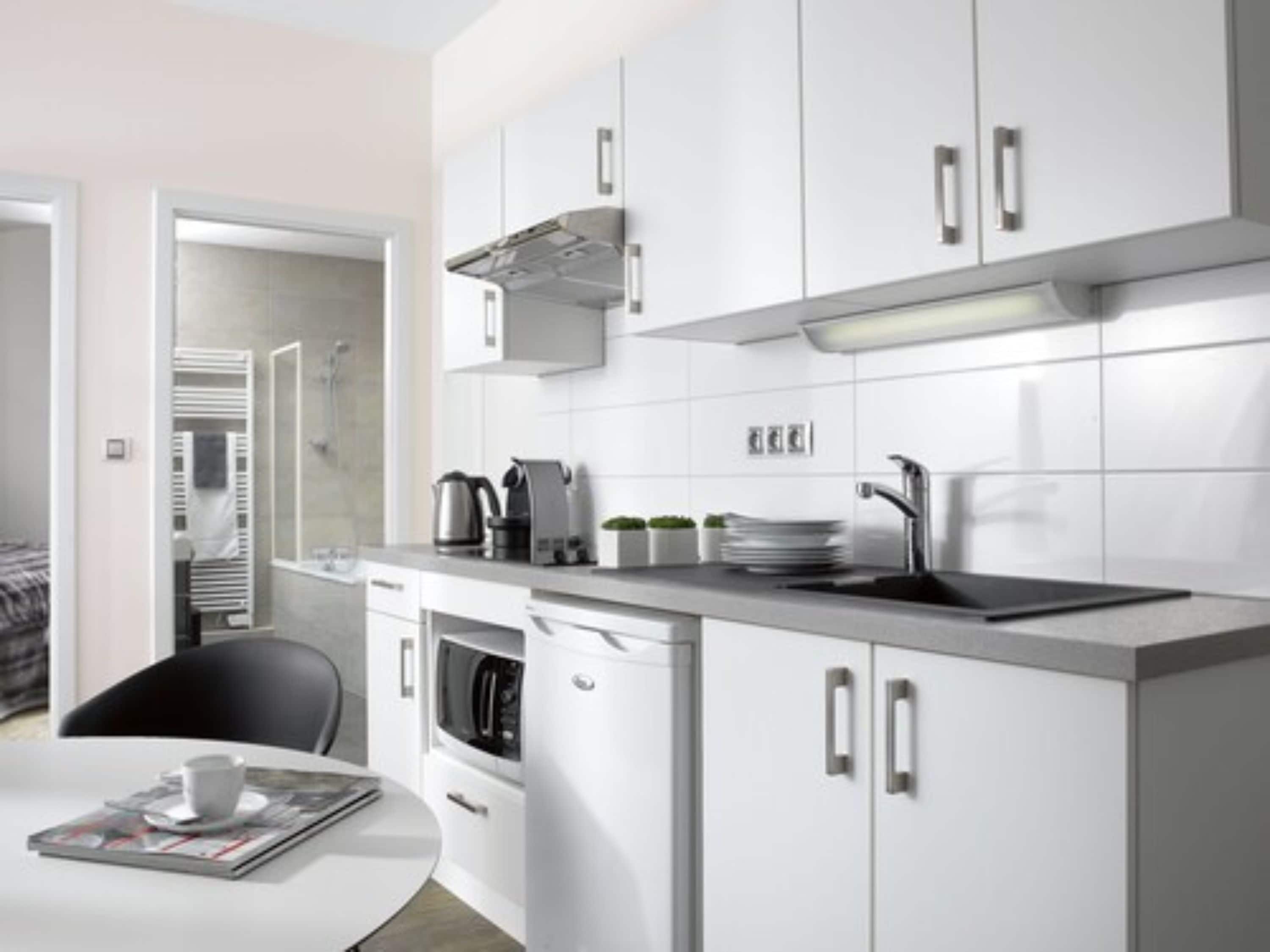 A modern kitchen with white cabinets, a built-in oven, and a coffee maker.