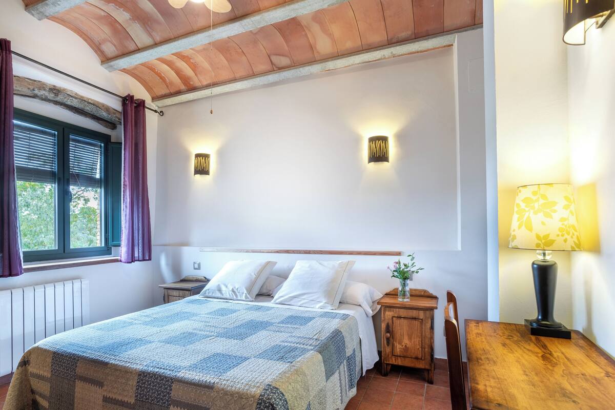 A bedroom with a bed, bedside tables, a lamp, and a window with curtains.