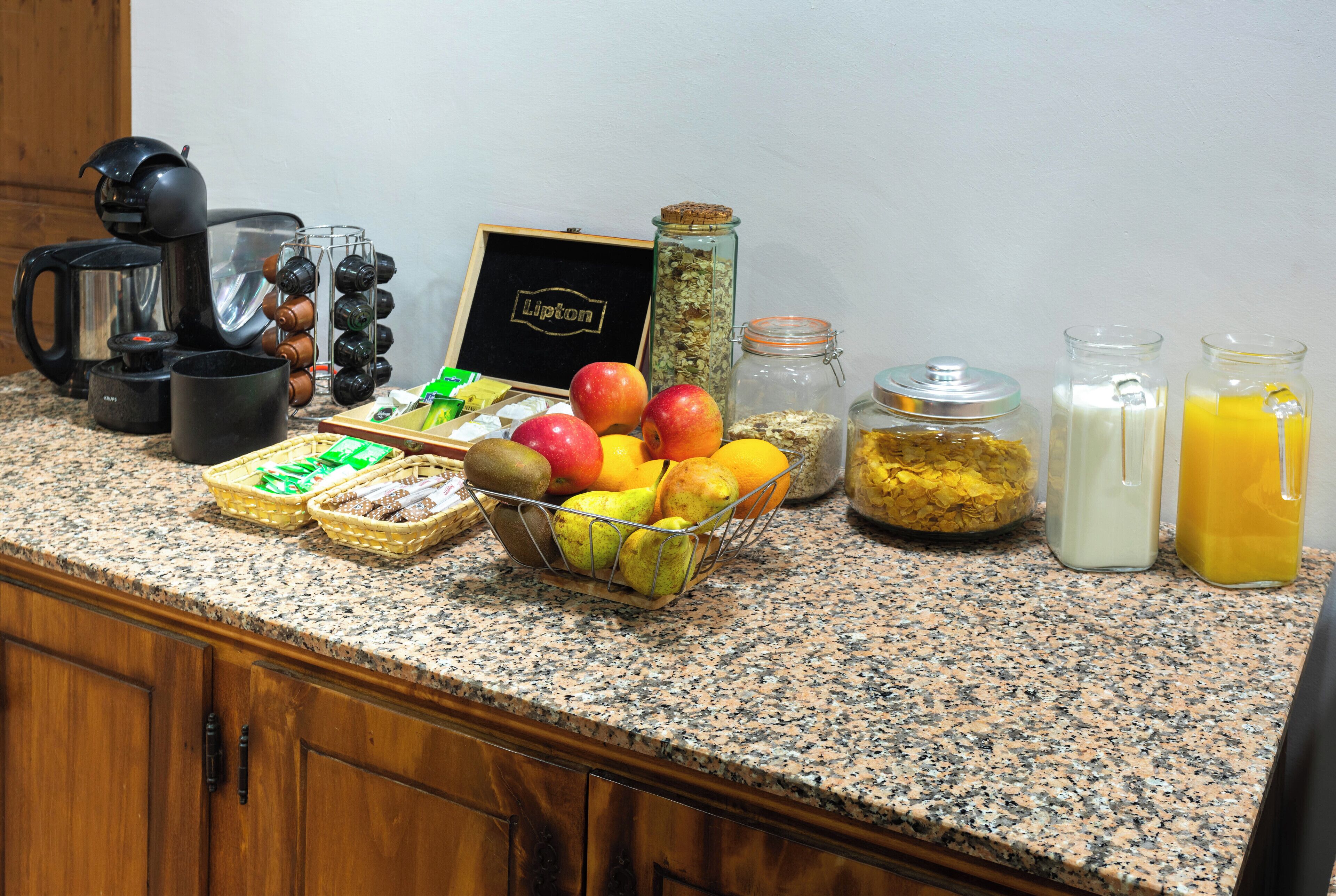 A kitchen counter with various breakfast items including fruits, coffee equipment, and condiments.