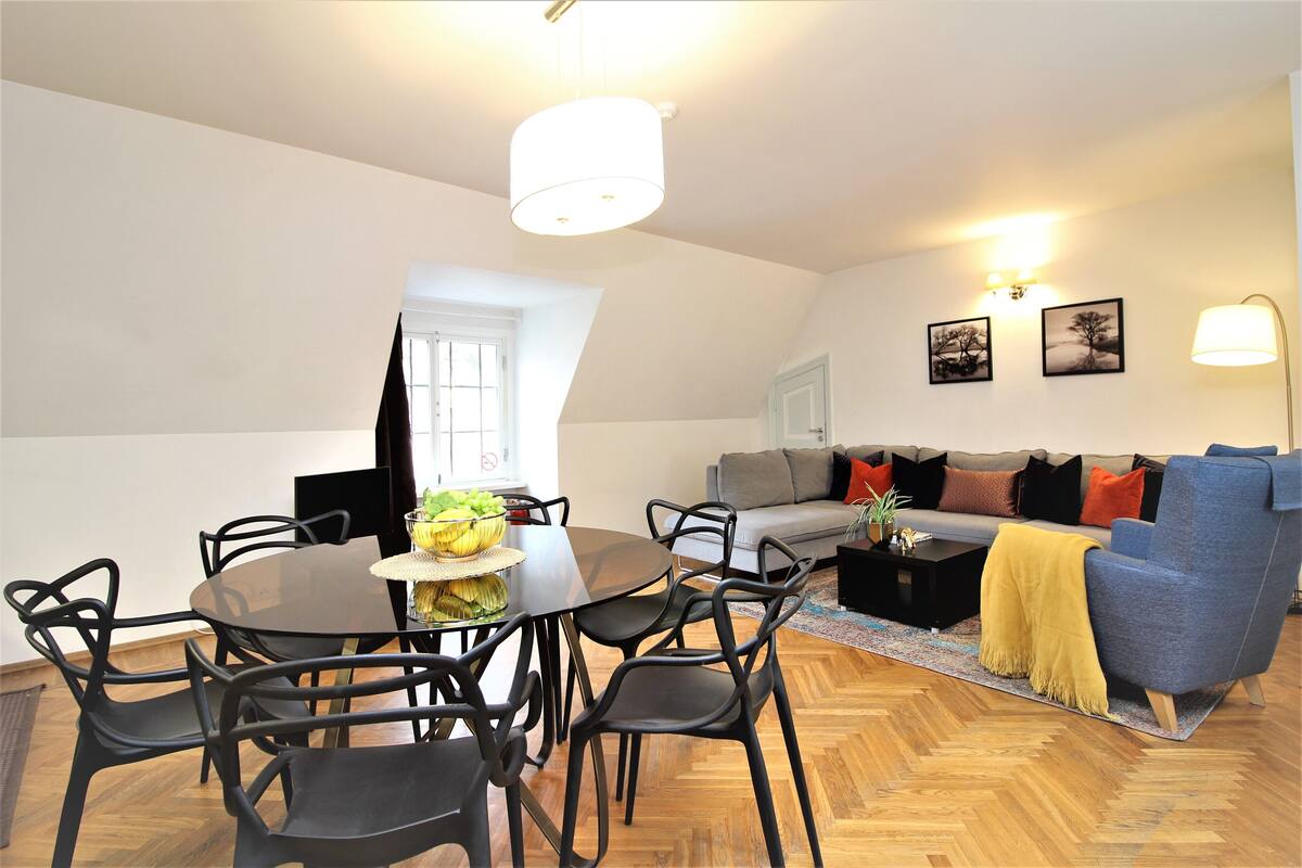 Ein Essbereich mit einem runden Tisch, Stühlen, einer Couch und einer Lampe.