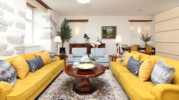 A living room with yellow sofas, a wooden coffee table, and a patterned rug. - Tallinn City Apartments Toompea Old Town (Tallinn)
