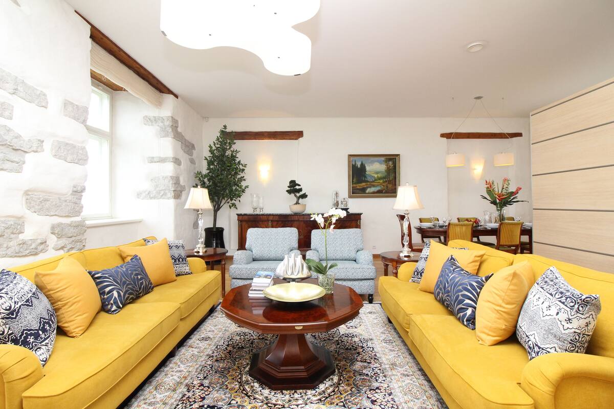Ein Wohnzimmer mit gelben Sofas, einem Holztisch und einem gemusterten Teppich.